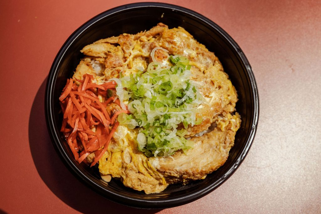 A large black bowl holding a Japanese dish.