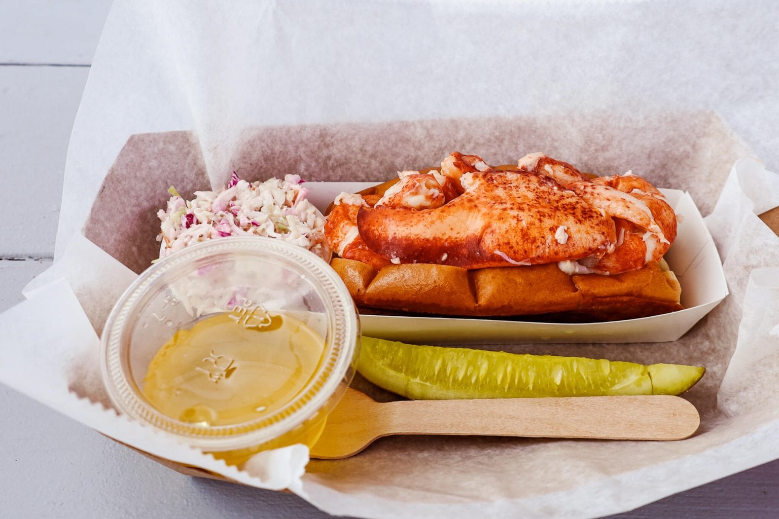 A lobster roll served with coleslaw.