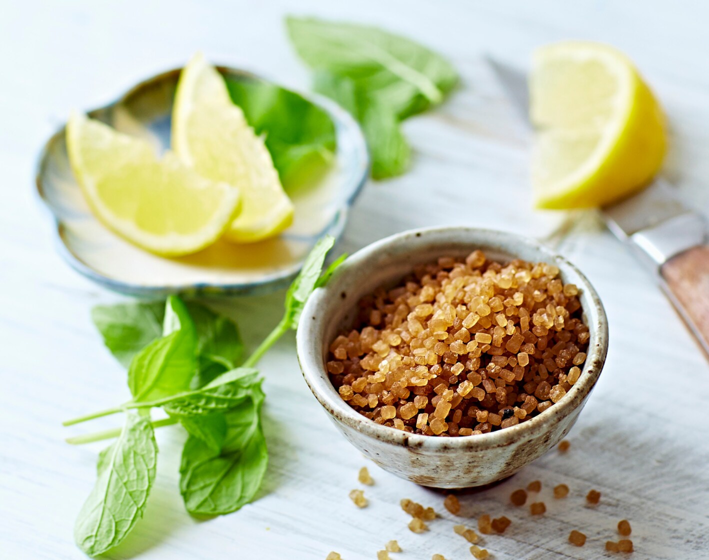 A small metal bowl of crushed herbs, with lemon wedges on the side.