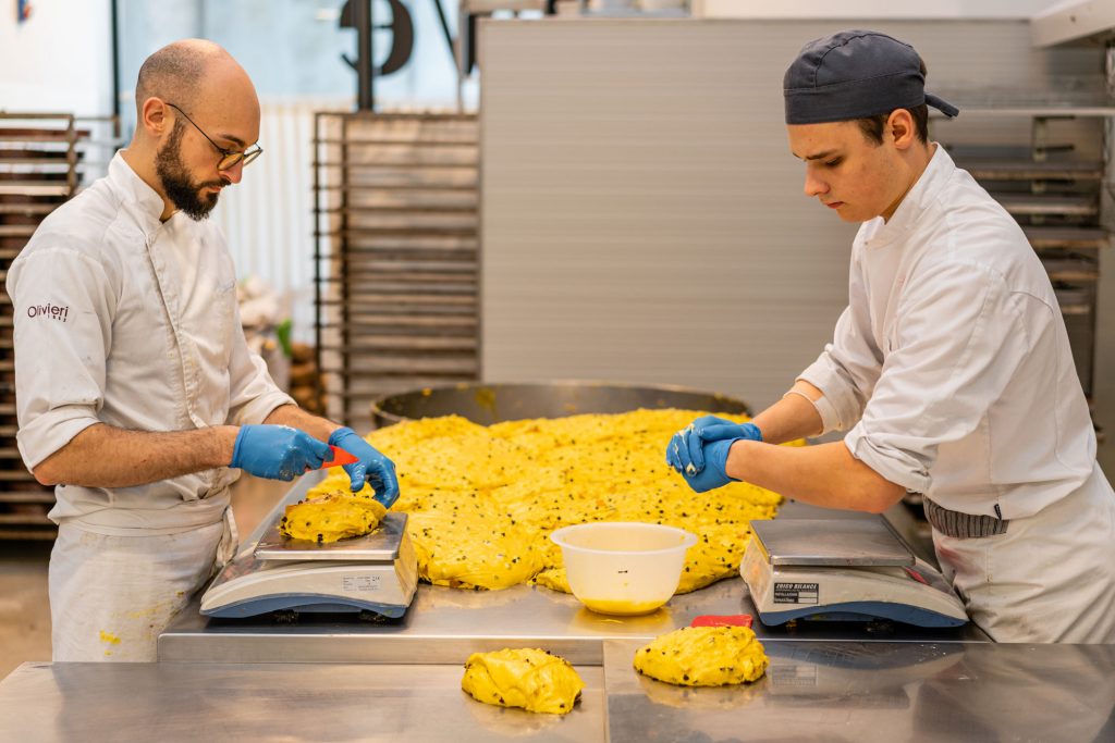 Bakers carefully portioning panettone dough.