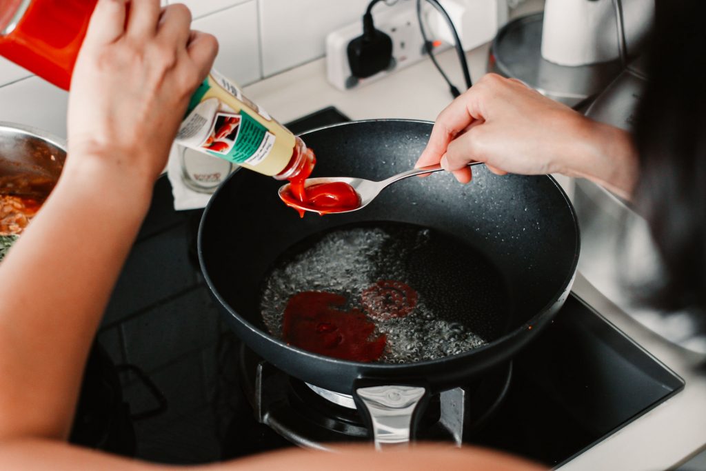Melly Fong pouring ketchup into a spoon.