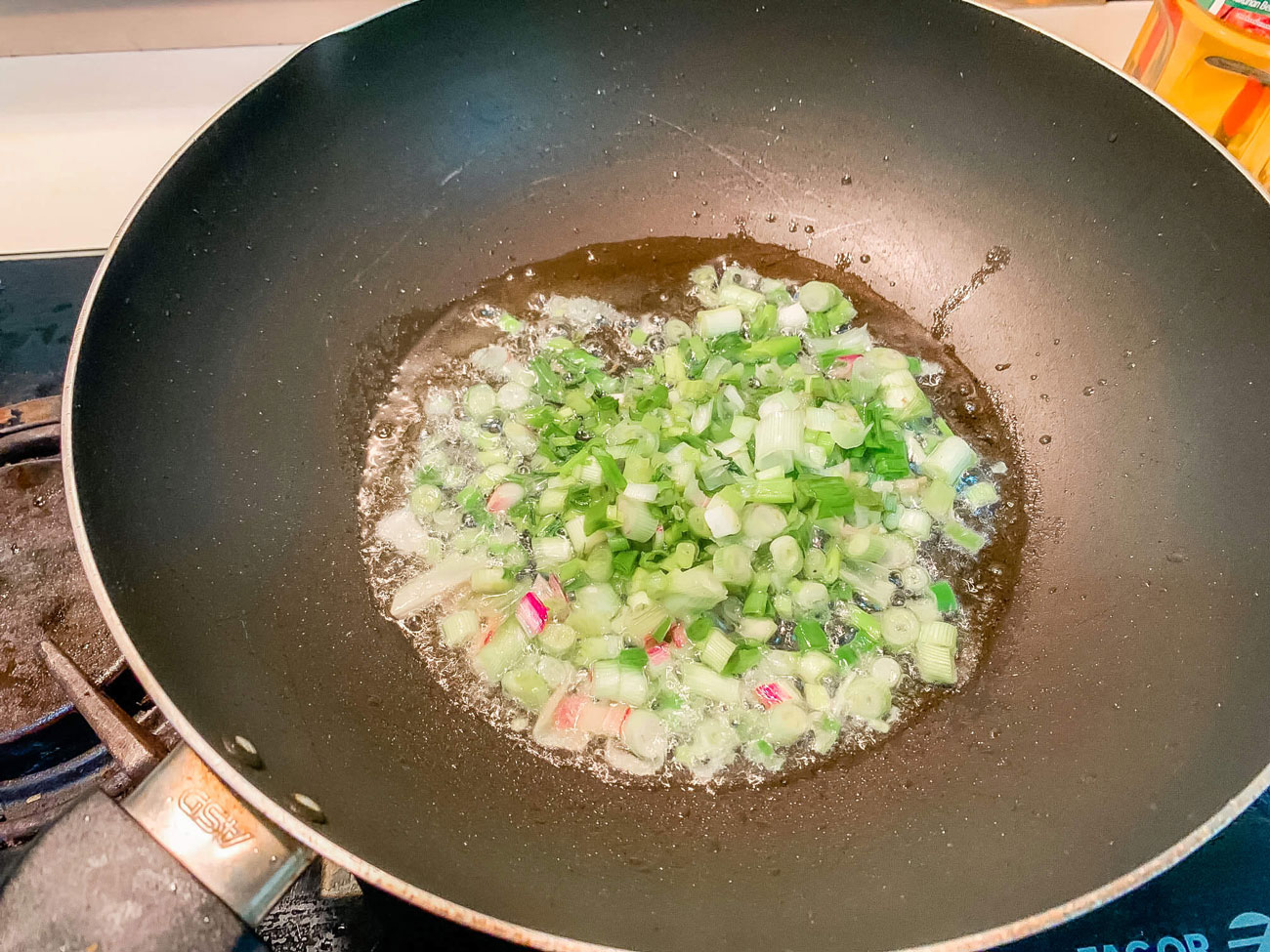 Chopped green onions frying in a wok.