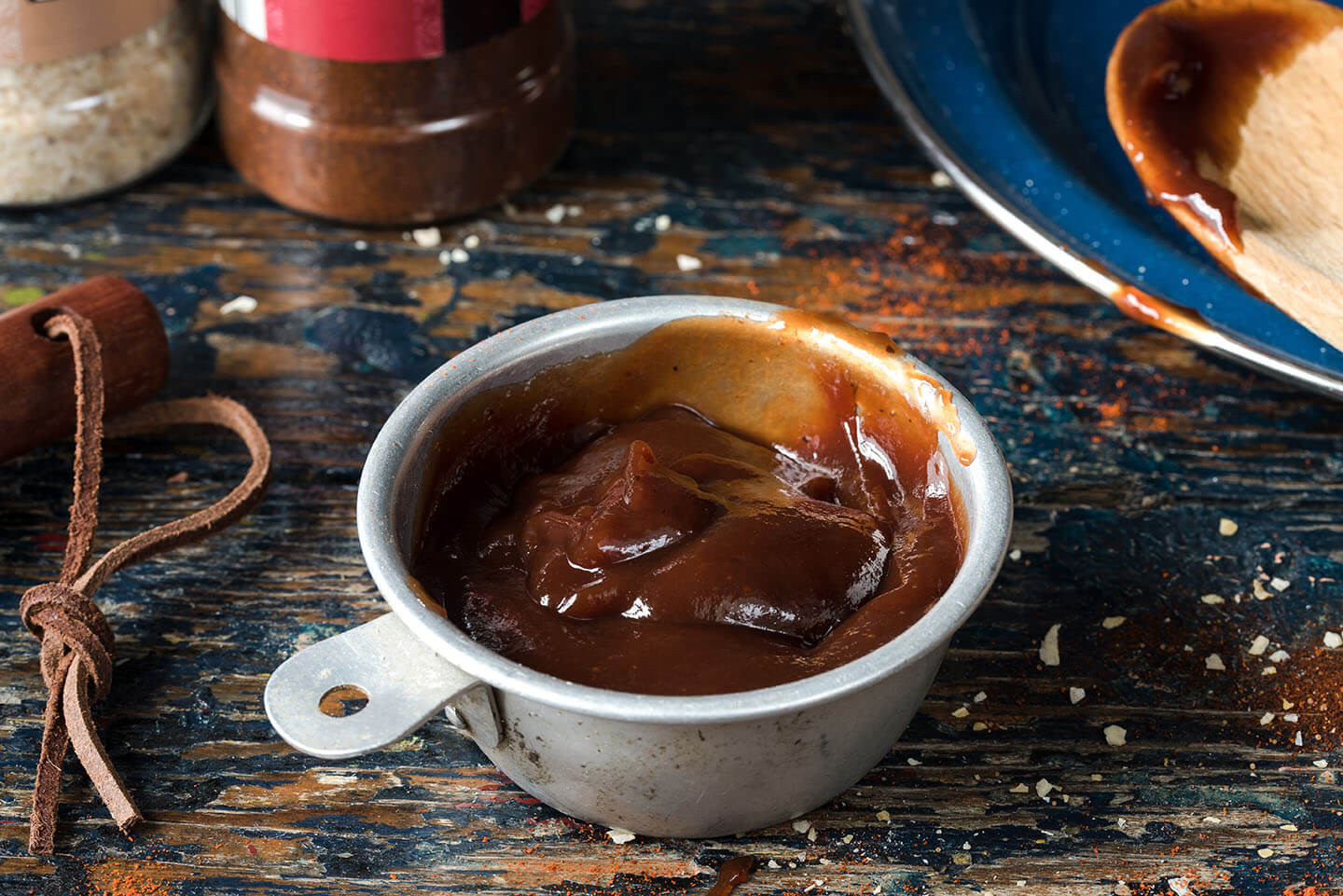 Barbeque sauce resting in a small metal bowl on a wooden table.