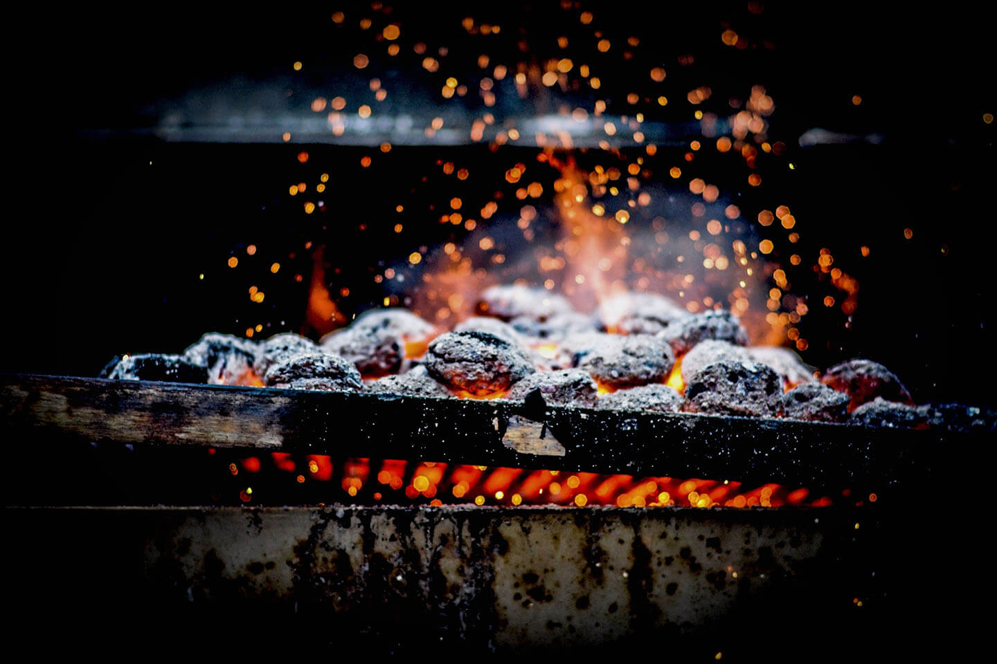 Charcoal burning into bright embers on a grill grate.
