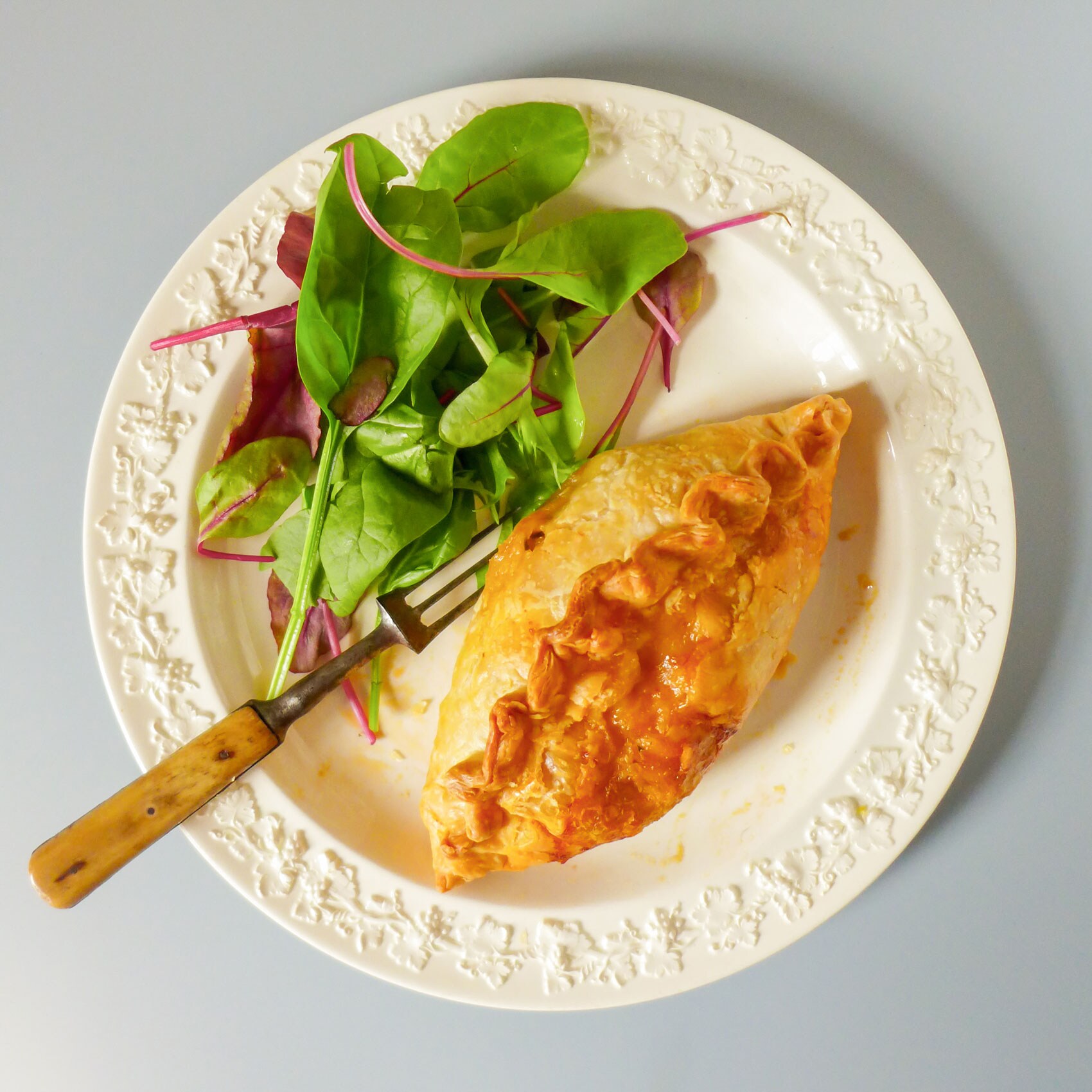 A toasted crab pasty resting on a plate.