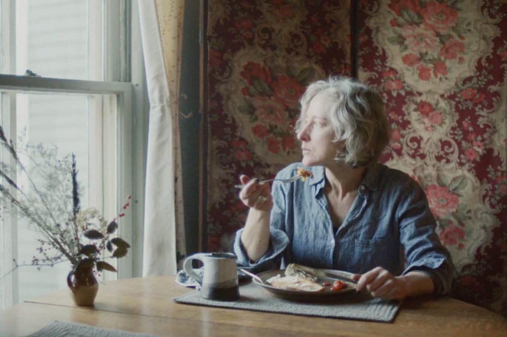 Erica gazing out the window as she eats her breakfast.