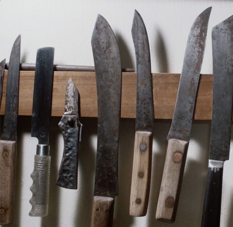 A variety of knives displayed on the wall.