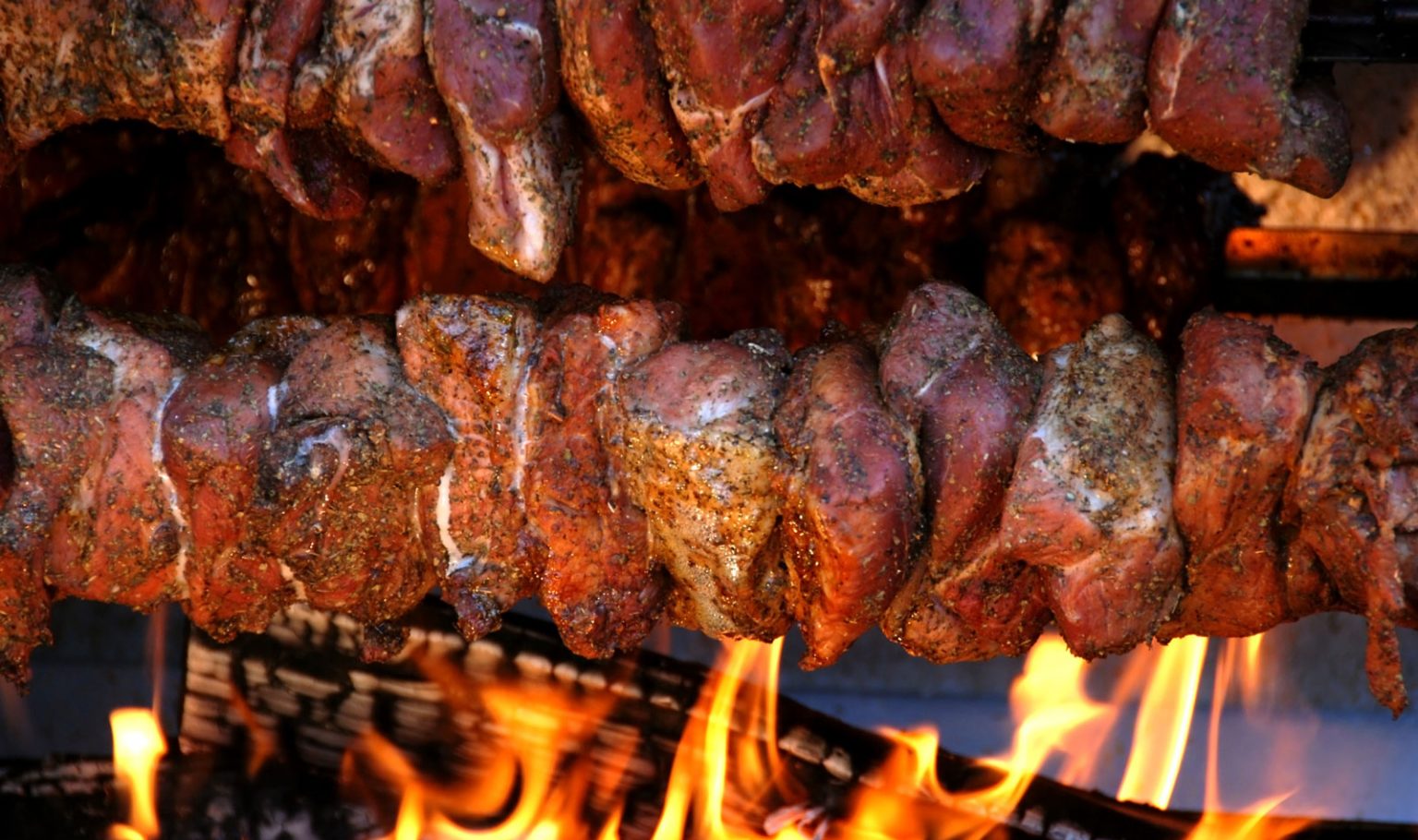Rotisseried pork gently cooking over a low flame.