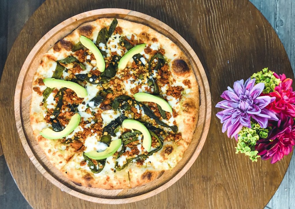 A wooden dish holding a Mexican pizza.