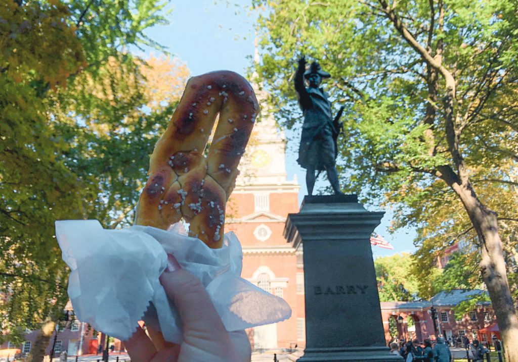 A person holding up a wrapped pretzel.
