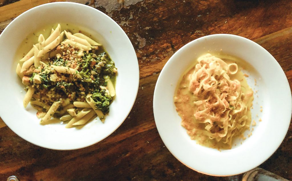 Two white dishes filled with freshly made pasta.