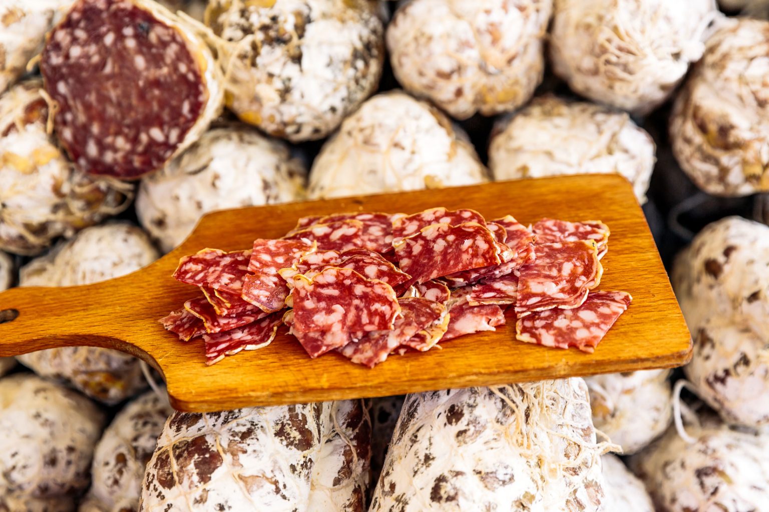 A wooden cutting board holding slices of fine meats.