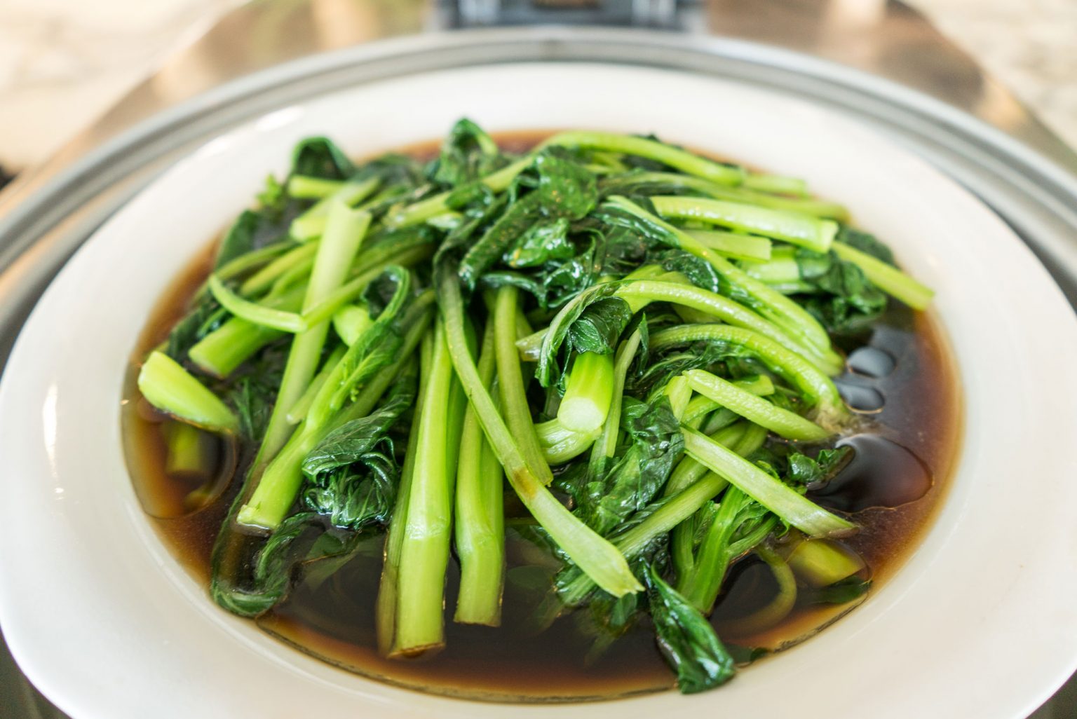 A bowl of freshly steamed greens resting in broth.