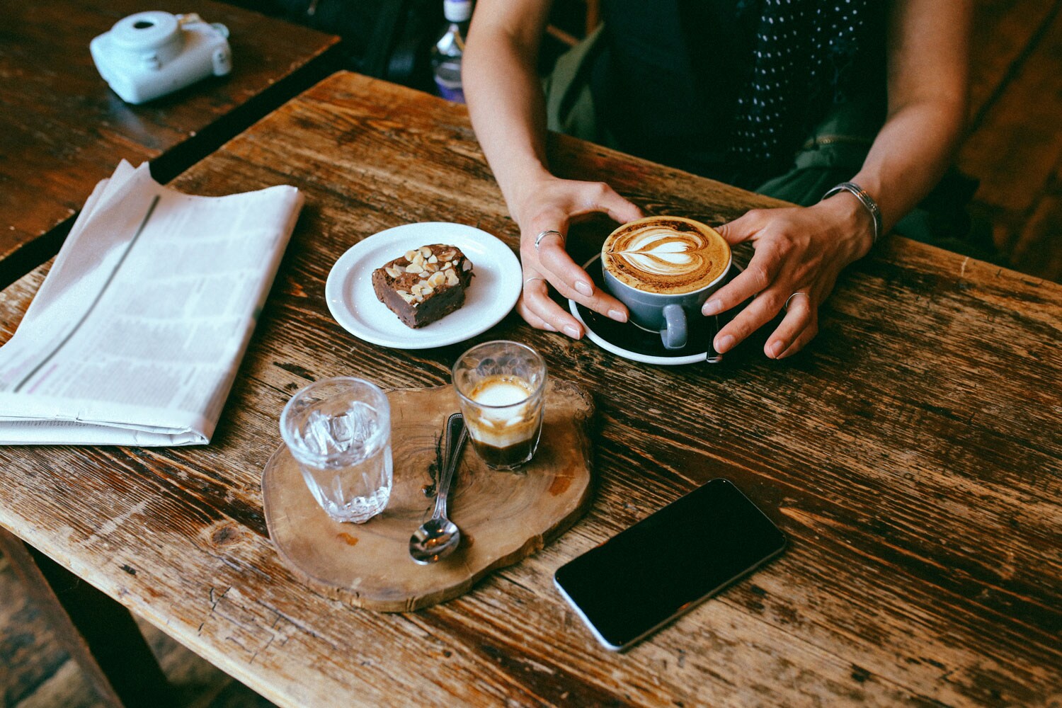 A person enjoying their intricate foam cappuccino at a coffee shop.