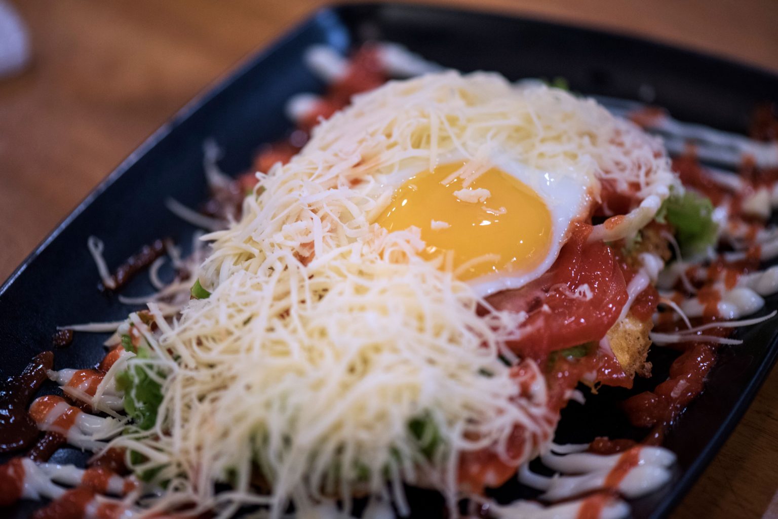An open roti john topped with cheese and an egg.