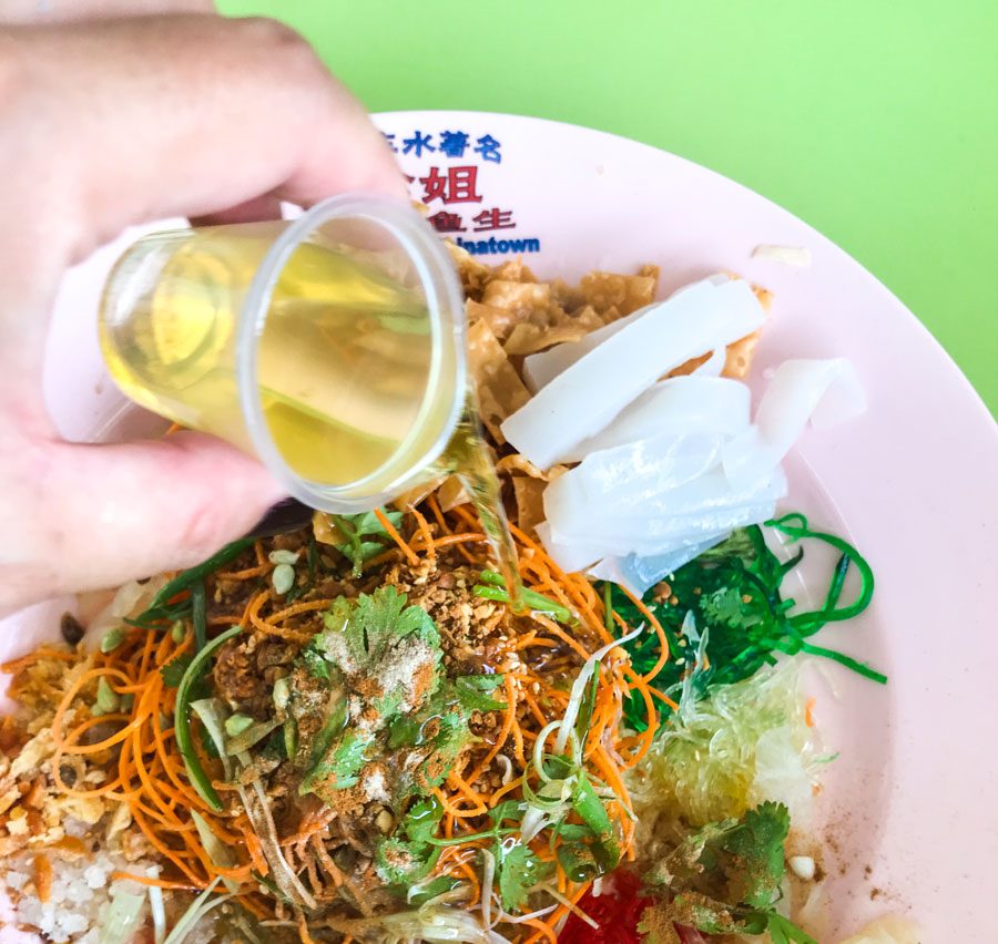 Someone pouring sesame oil on yusheng.