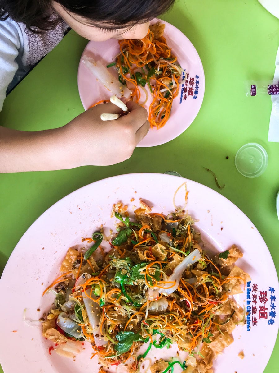 Someone taking a portion from a bowl of yusheng.