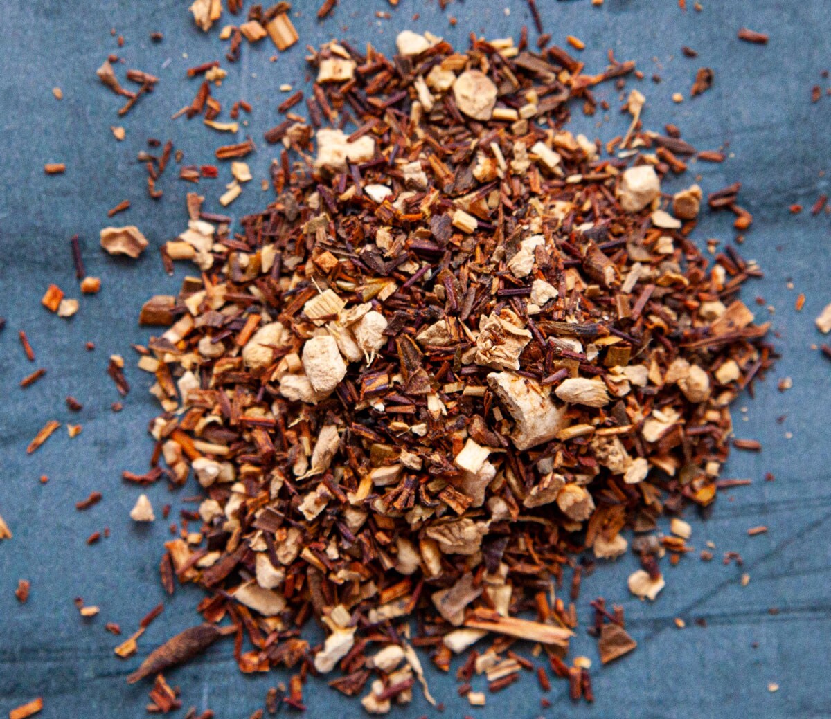 A pile of various tea leaves resting on a blue table.