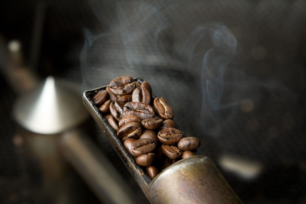 A small scoop of freshly roasted coffee beans.