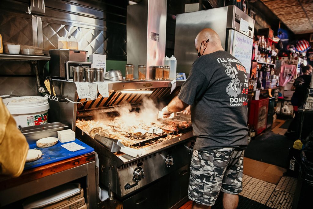 A person working diligently working at the grill at Donkey's Place.