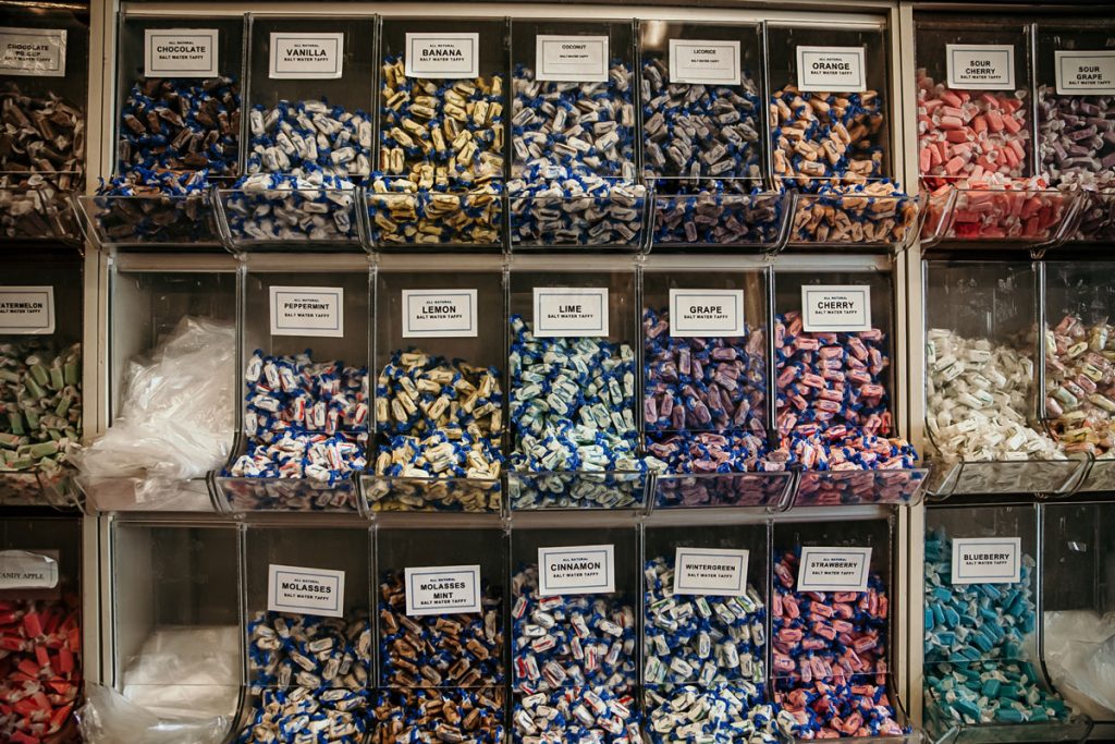 Individual tubs labeled and filled with a variety of salt water taffy flavors.