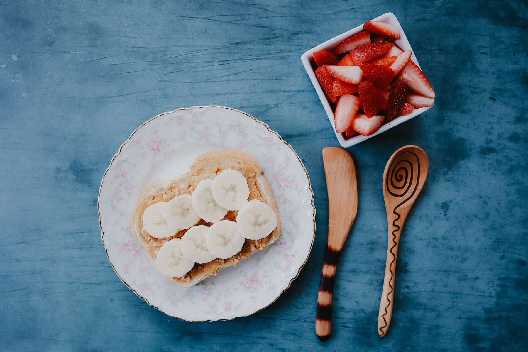 A delicate plate of food paired with intracate wooden utensils.