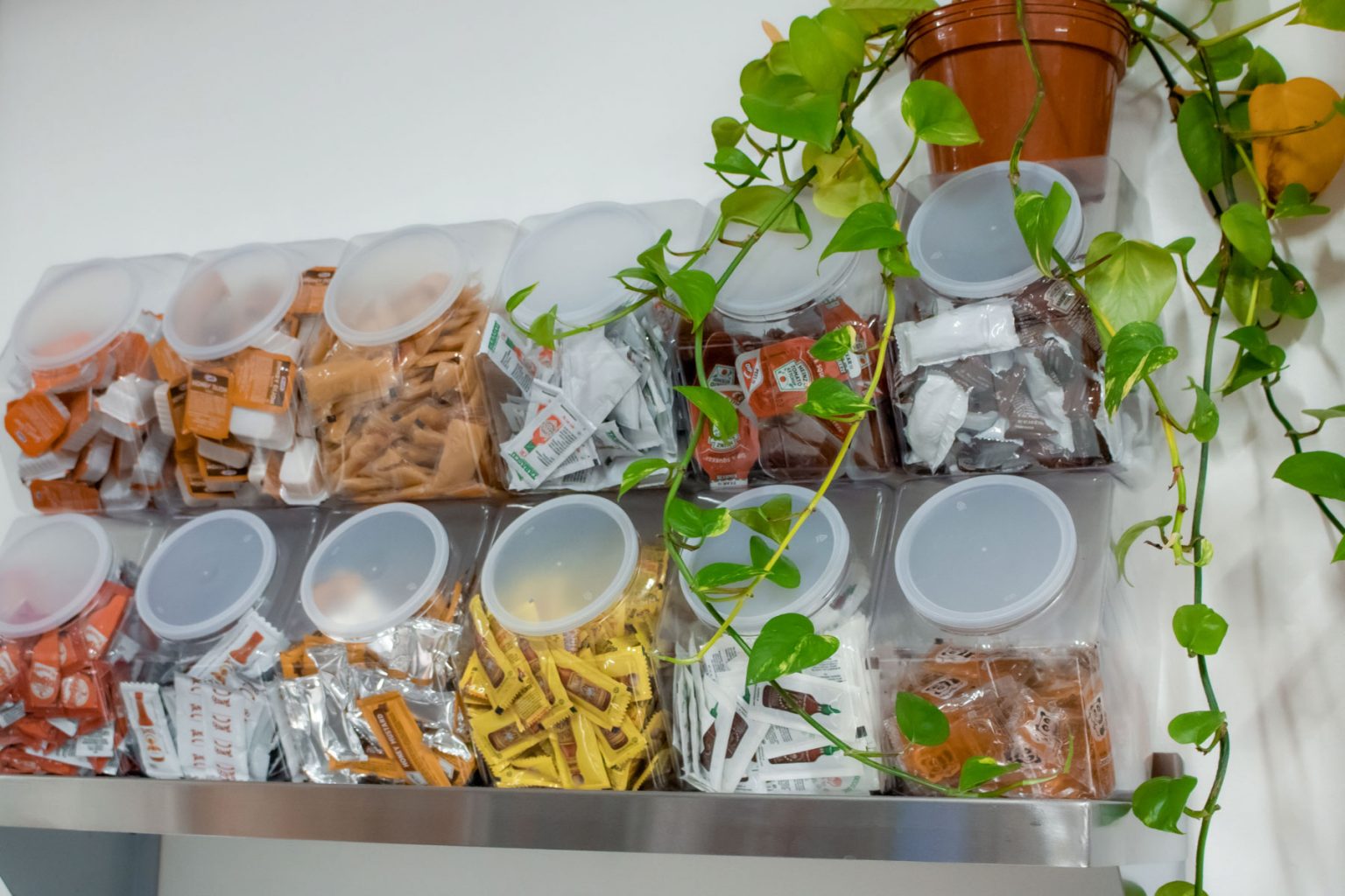 Individual storage containers filled with a variety of sauce packets and containers.