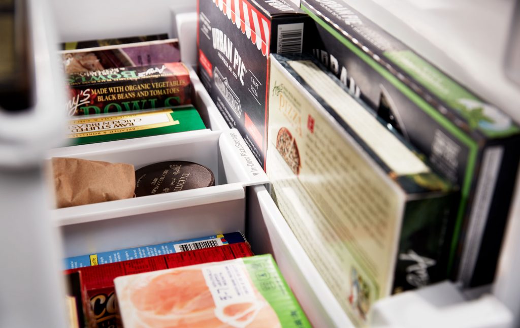 A freezer filled with a variety of frozen food boxes and containers.