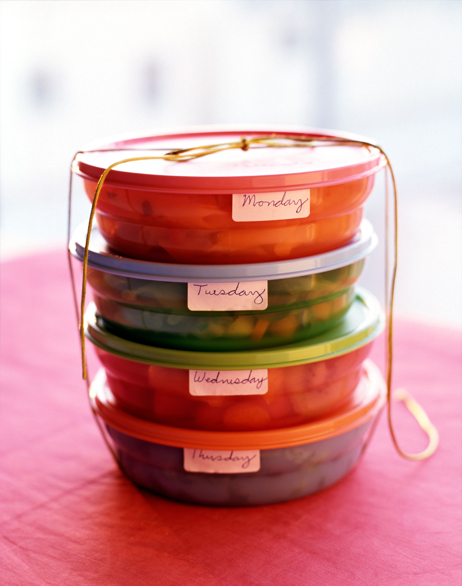 Four stacked food containers labeled with days of the week.