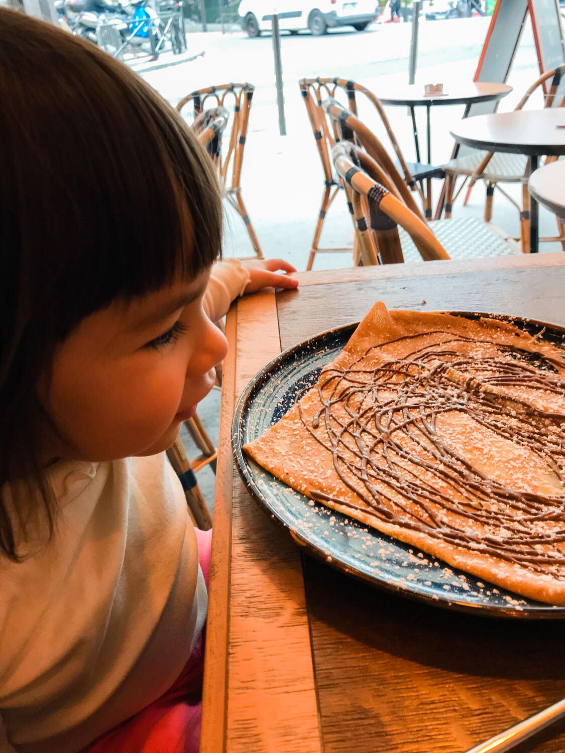 A crepe drizzled in chocolate served for a young child.