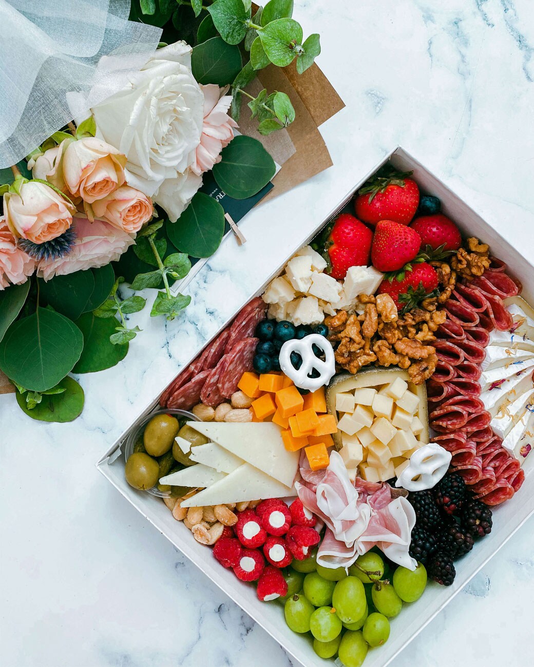 A picnic box filled with a variety of meats and cheeses.