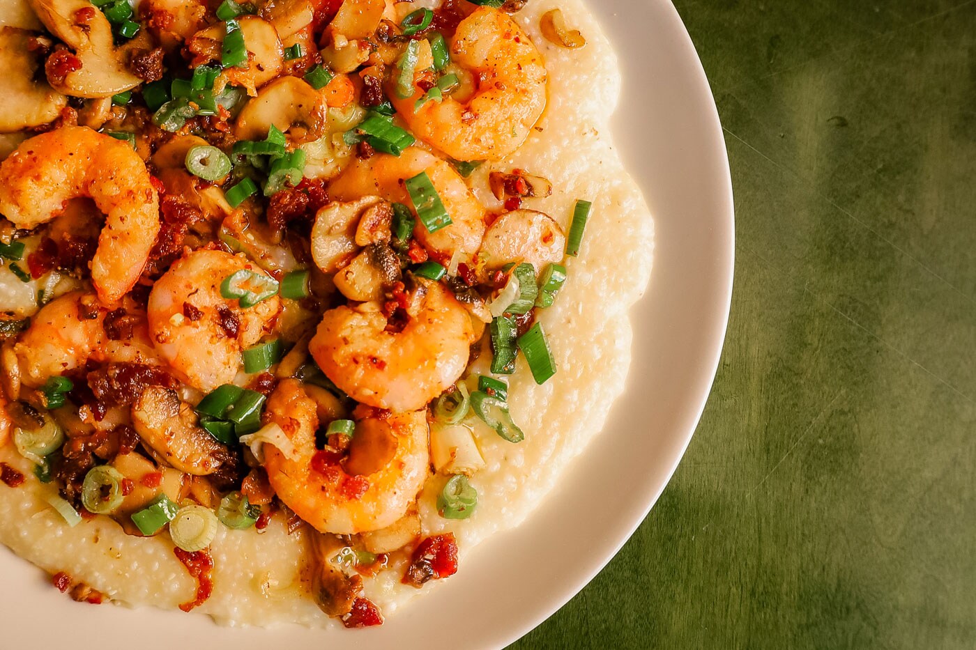 A closeup of a big, white bowl of shrimp and creamy grits.