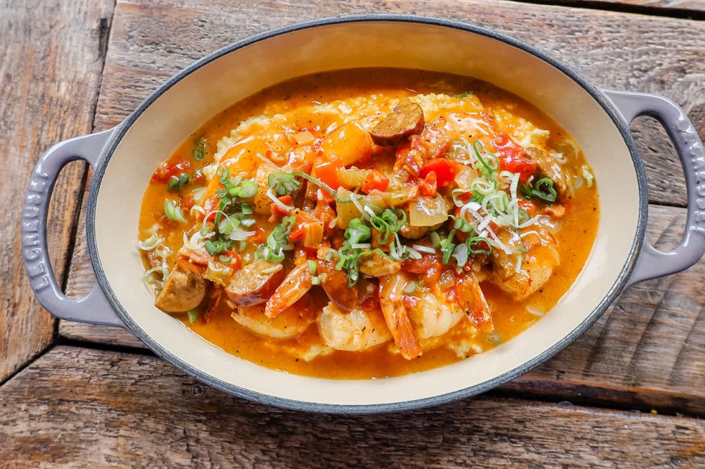 An overhead shot of an oval dish filled with cajun shrimp and grits.
