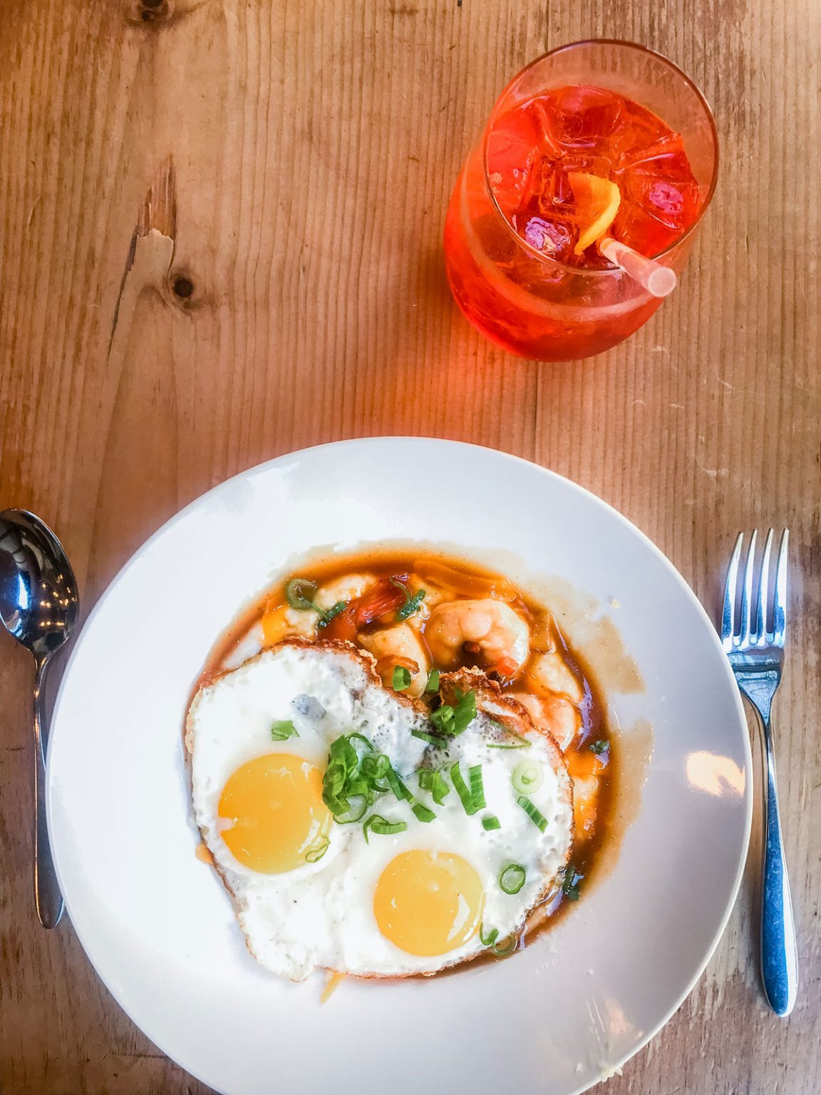 A fried egg resting on top of a bowl of shrimp and grits.