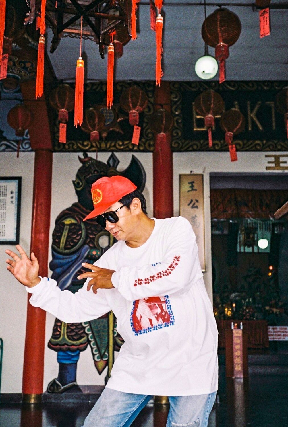 Paulus Supomo in sunglasses and red hat doing kung fu moves.