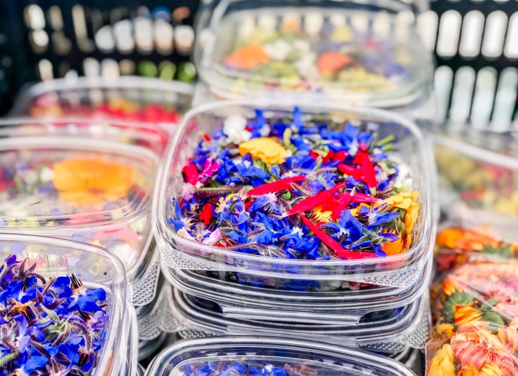 Clear containers filled with a variety of edible flowers.