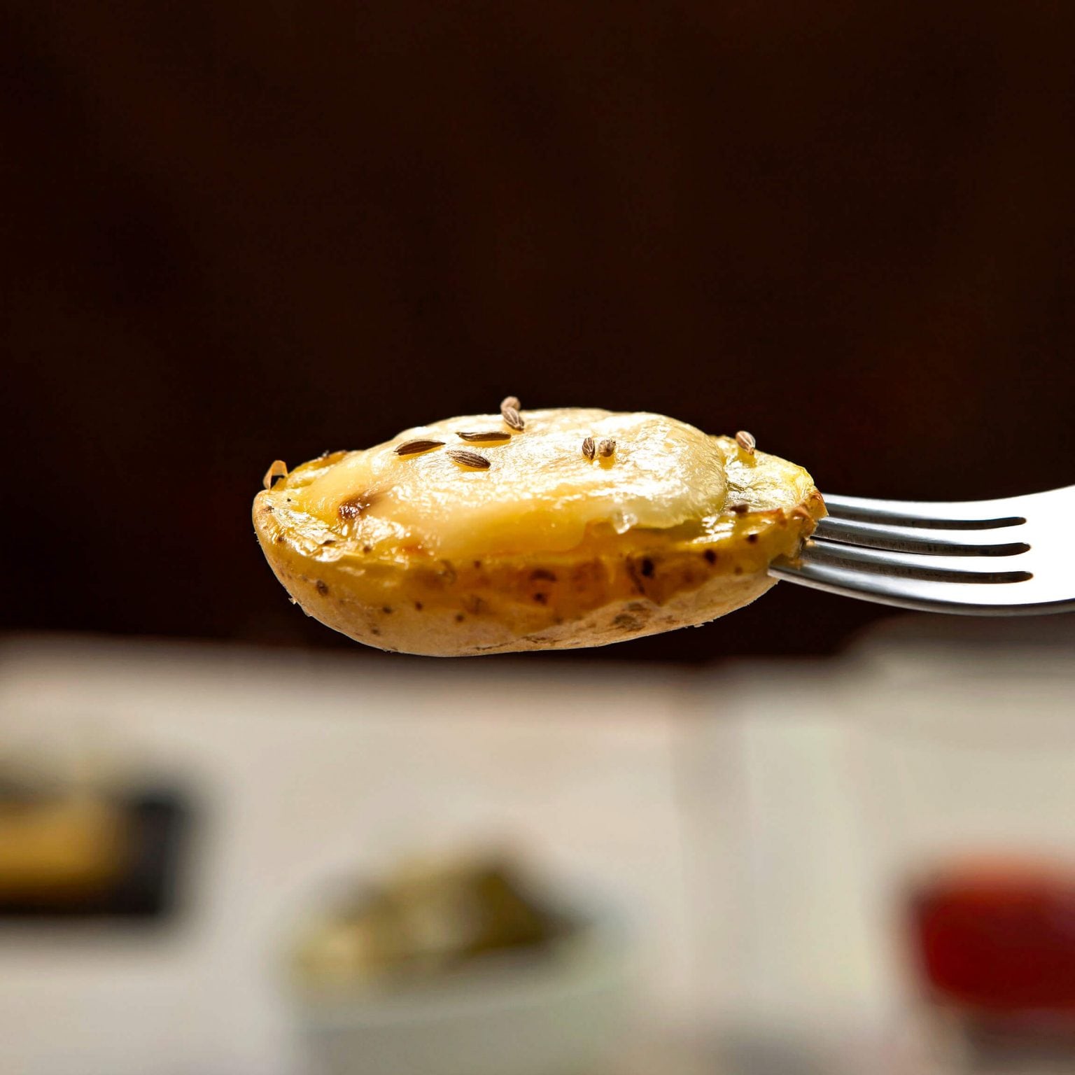 A single fork holding a small, halved potato topped with melted cheese.