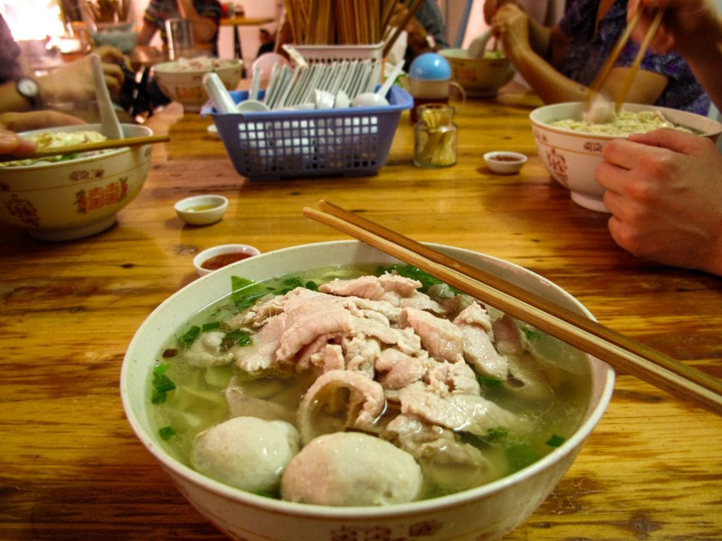 A bowl of soup accompanied by chopsticks.