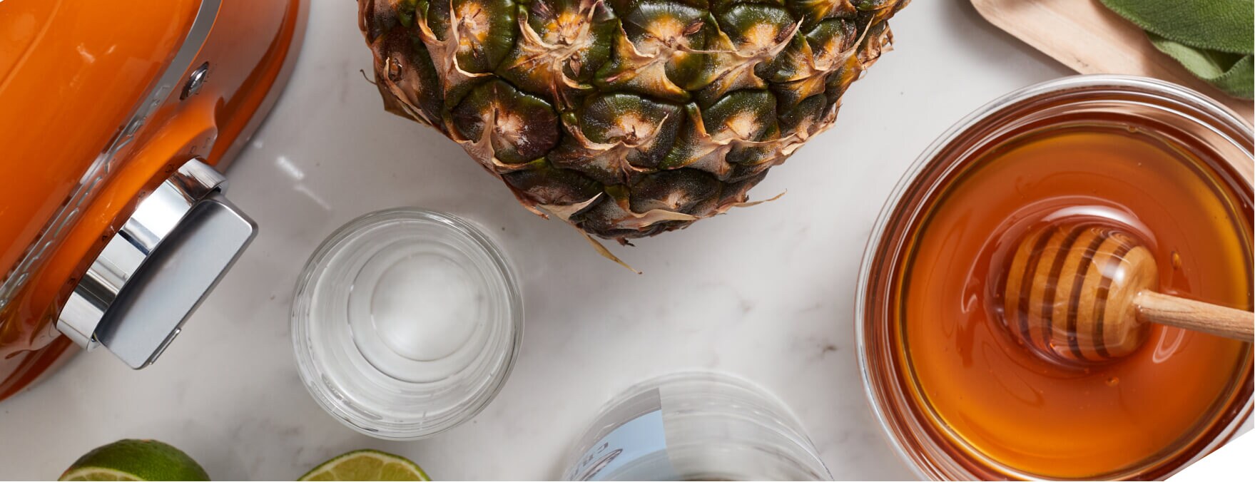 Overhead shot of KitchenAid® Honey colored blender surrounded by fresh pineapple, honey and limes.