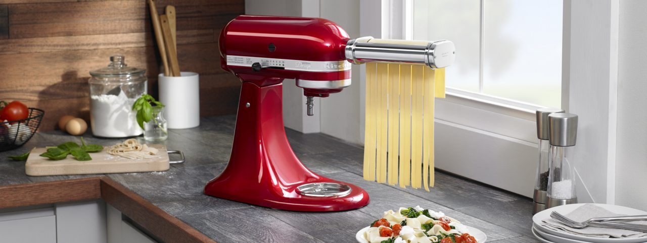 KitchenAid® stand mixer with pasta attachment cutting dough into ribbons