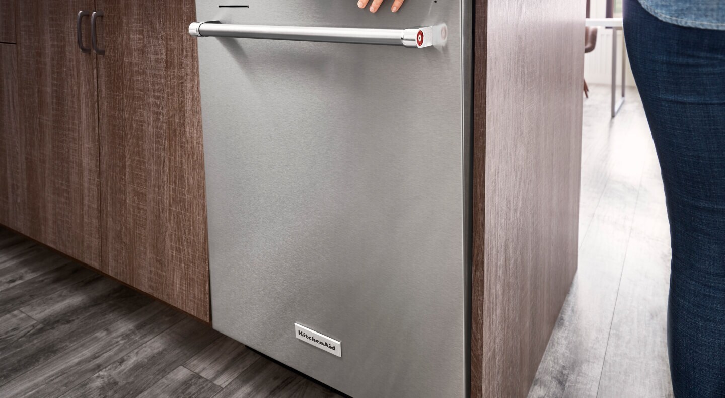 Person closing a top control dishwasher with towel bar handle