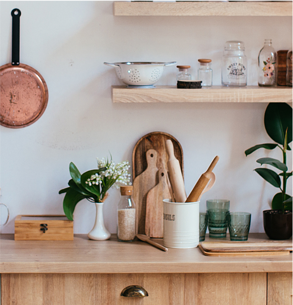 A white and light-wood kitchen with copper pans and open shelving.