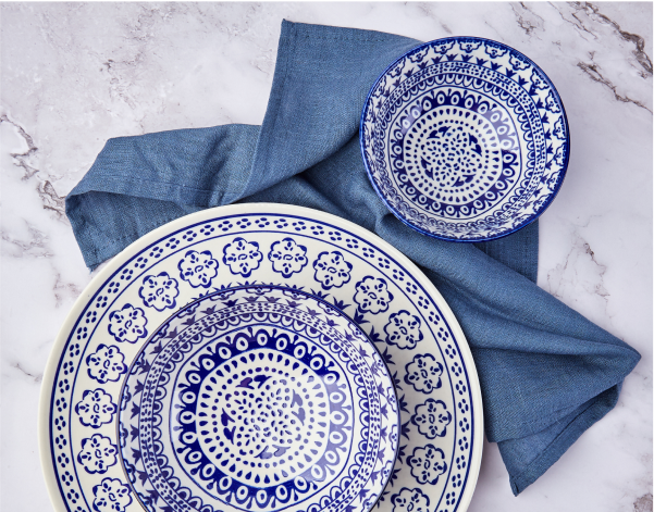 A series of intricately designed blue and white dishes sitting on a blue linen napkin.