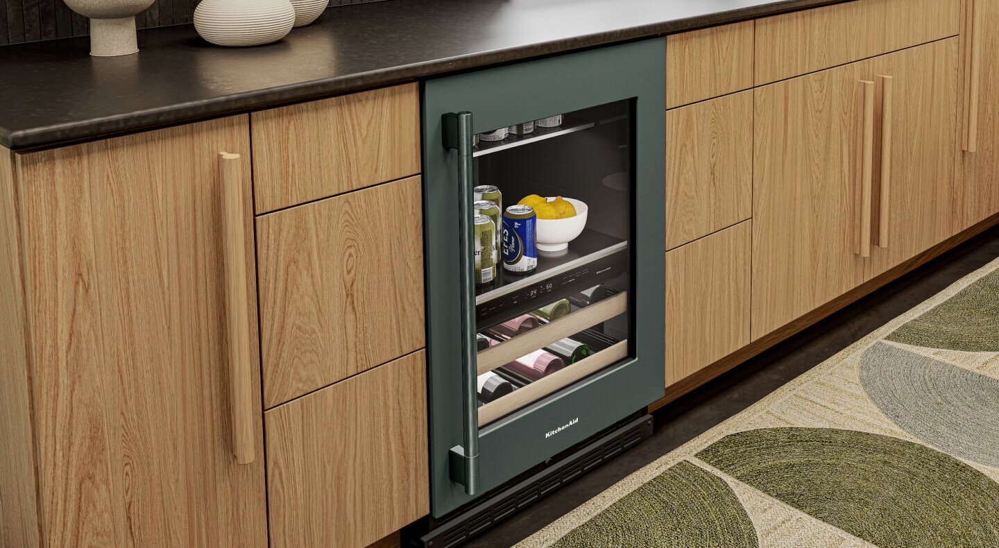 A KitchenAid® beverage center with a glass door amid wooden cabinetry
