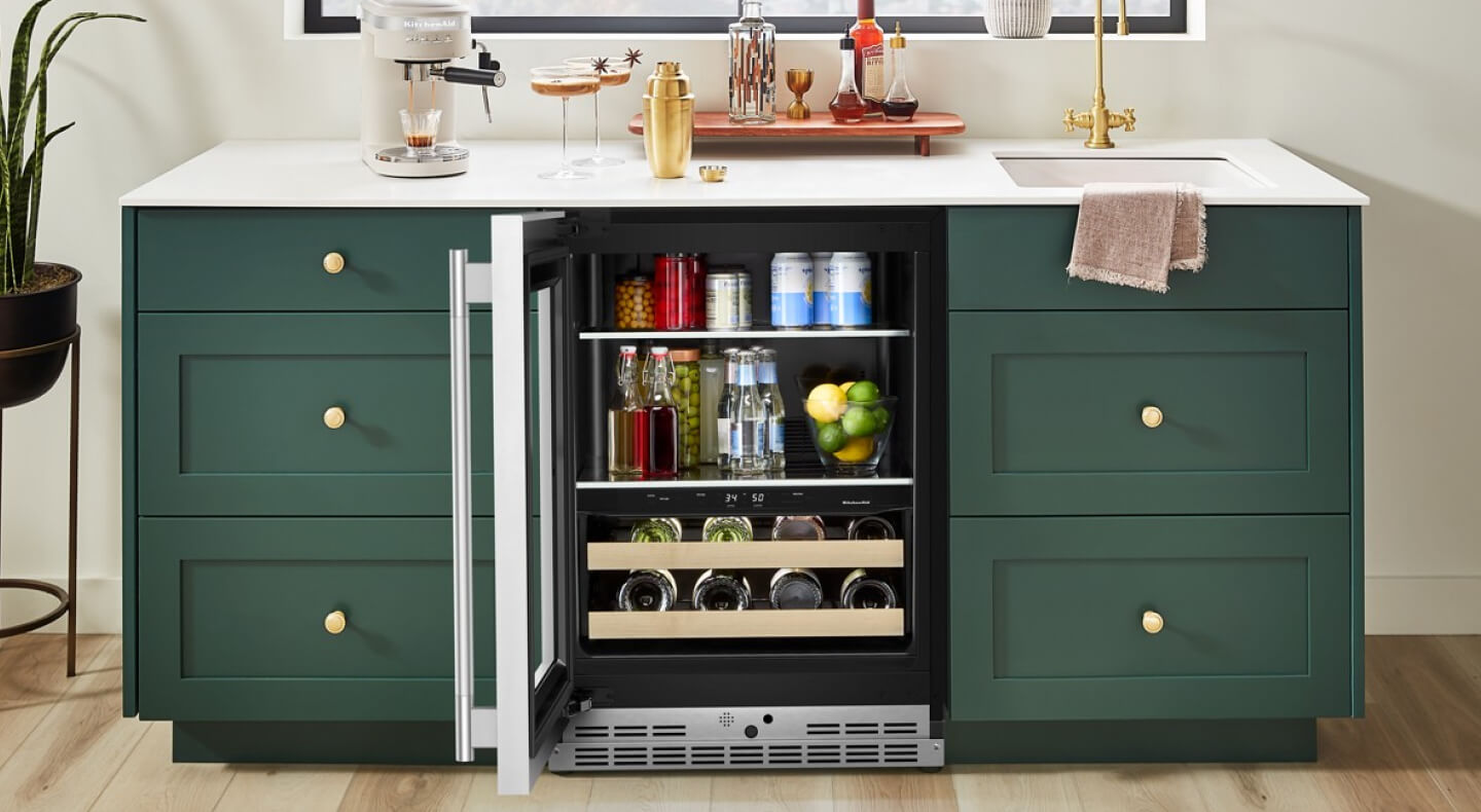 An open beverage center surrounded by teal cabinetry