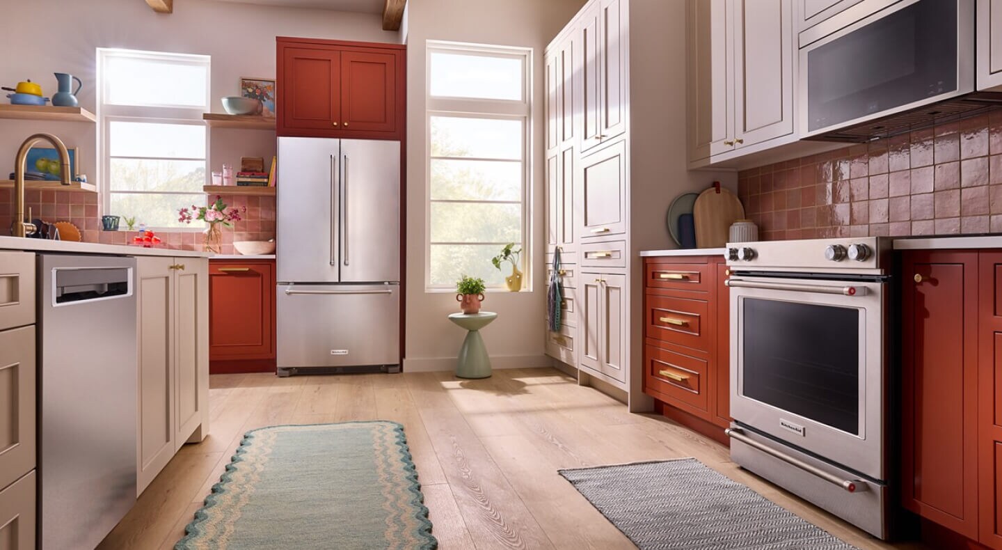 Suite of KitchenAid® stainless steel appliances in vibrant orange cabinetry