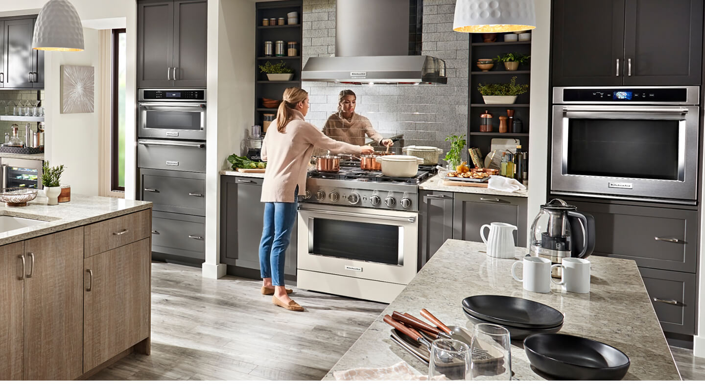 A woman cooking on a KitchenAid® range in a modern kitchen.