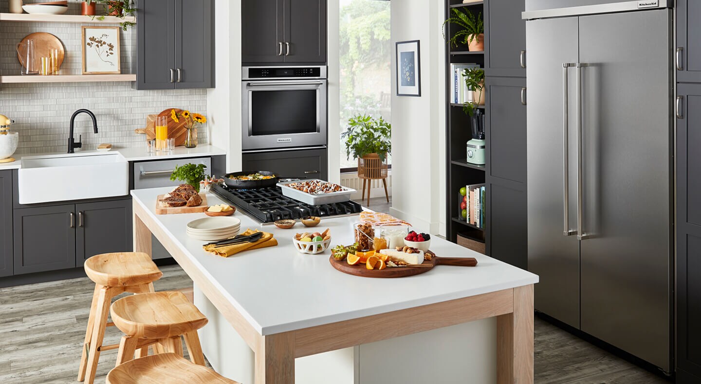 A stylish, modern kitchen filled with KitchenAid® appliances and prepared dishes on the island A stylish, modern kitchen filled with KitchenAid® appliances and prepared dishes on the island