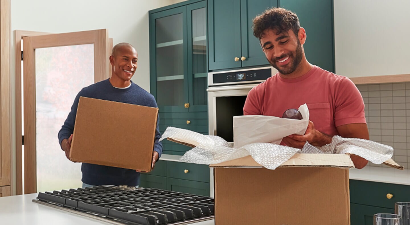 Two men moving and unpacking boxes in a remodeled kitchen Two men moving and unpacking boxes in a remodeled kitchen