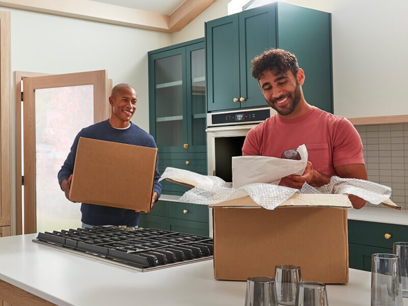 Two men moving and unpacking boxes in a remodeled kitchen Two men moving and unpacking boxes in a remodeled kitchen